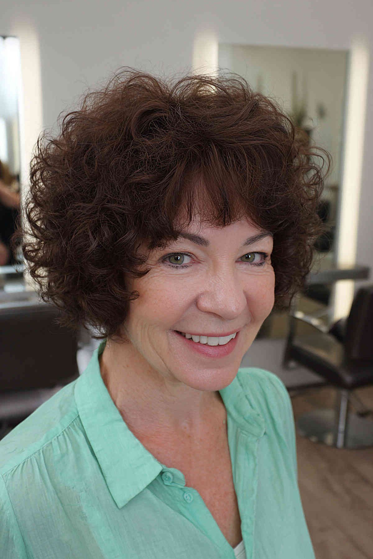 Dark brown curly bob with full bangs for women over 60