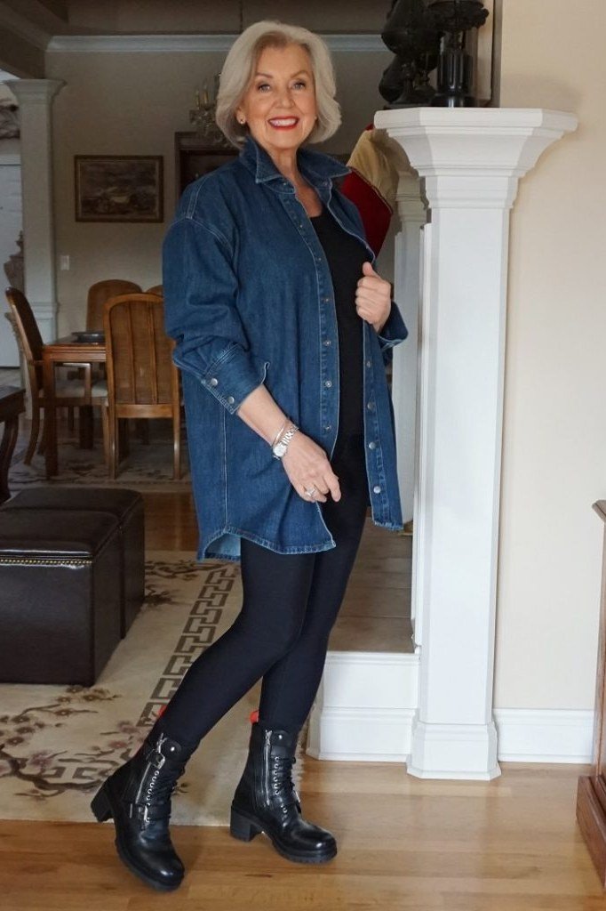 Blonde older woman in denim shirt dress with black leggings and boots, hallway interior - denim dresses for women over 60