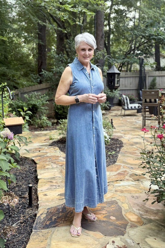 Older woman in sleeveless chambray maxi shirt dress, garden path - denim dresses for women over 60