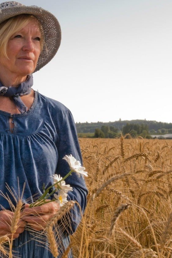 Older woman in denim shirt dress with straw hat, wheat field - denim dresses for women over 60