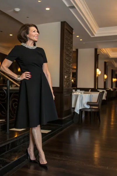 Black fit-and-flare dress with sheer neckline in a restaurant for older women
