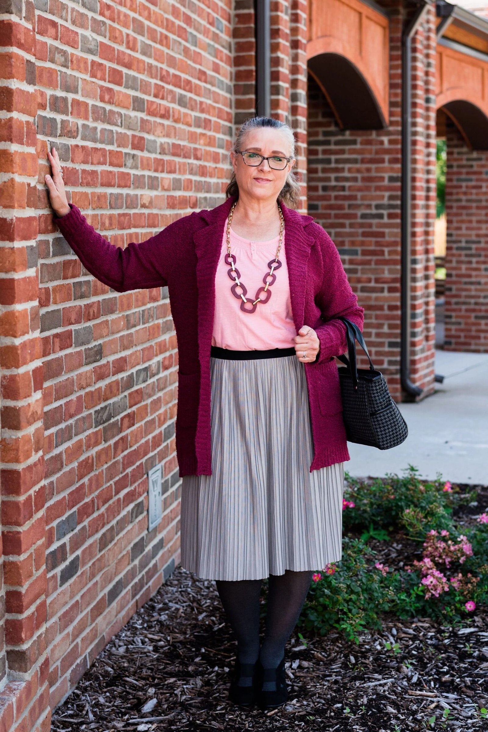 Burgundy cardigan with pink top and gray pleated skirt for older women