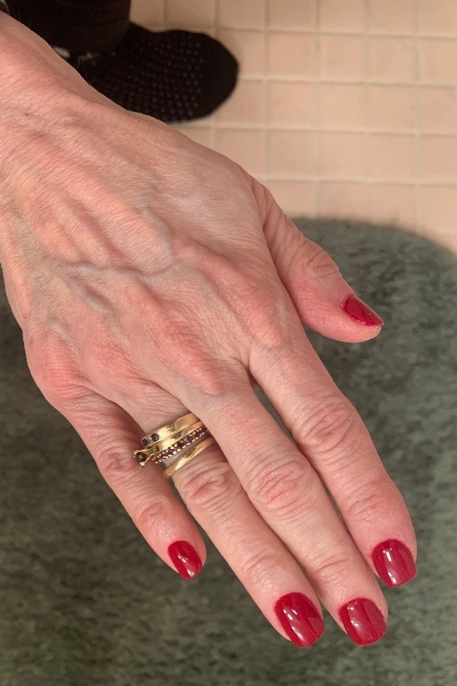 Classic red nails with gold rings, elegant nail idea for women over 50