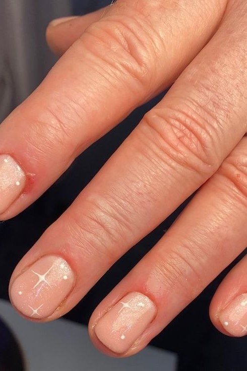 Sheer peachy-nude nails with star sparkles, elegant nail idea for women over 50
