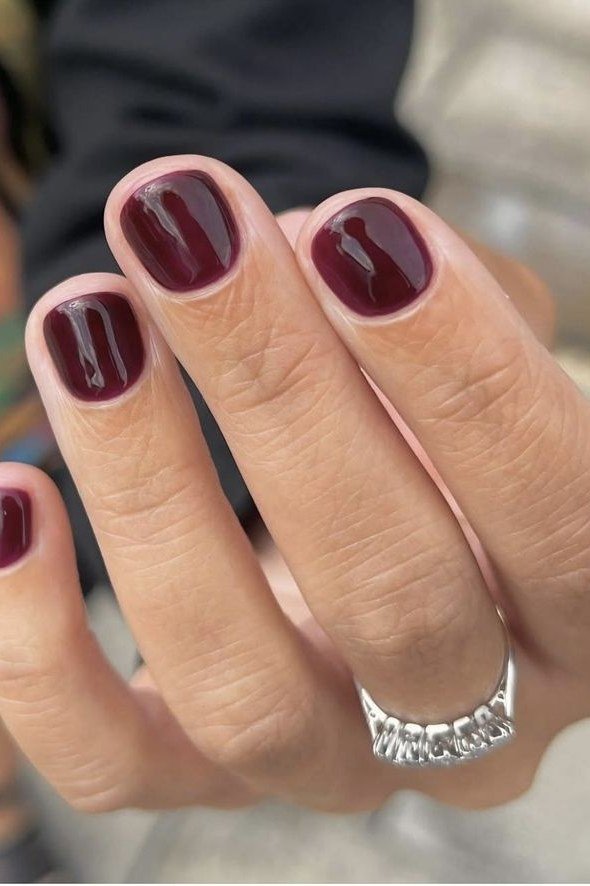 Deep wine-red glossy nails close-up, elegant nail idea for women over 50