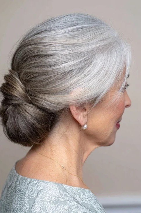 Low grey bun in profile in silver dress, an elegant updo for women over 70