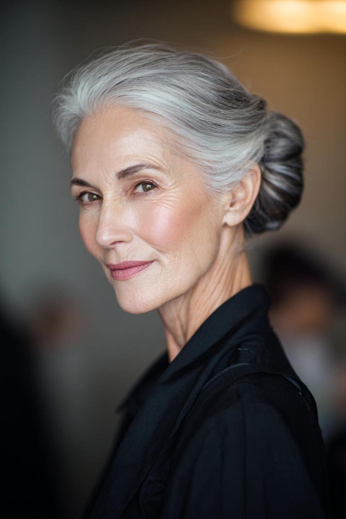 Grey low bun three-quarter view in dark top, an elegant updo for women over 70