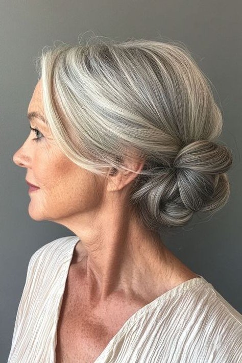 Silver low bun in profile in white blouse, an elegant updo for women over 70