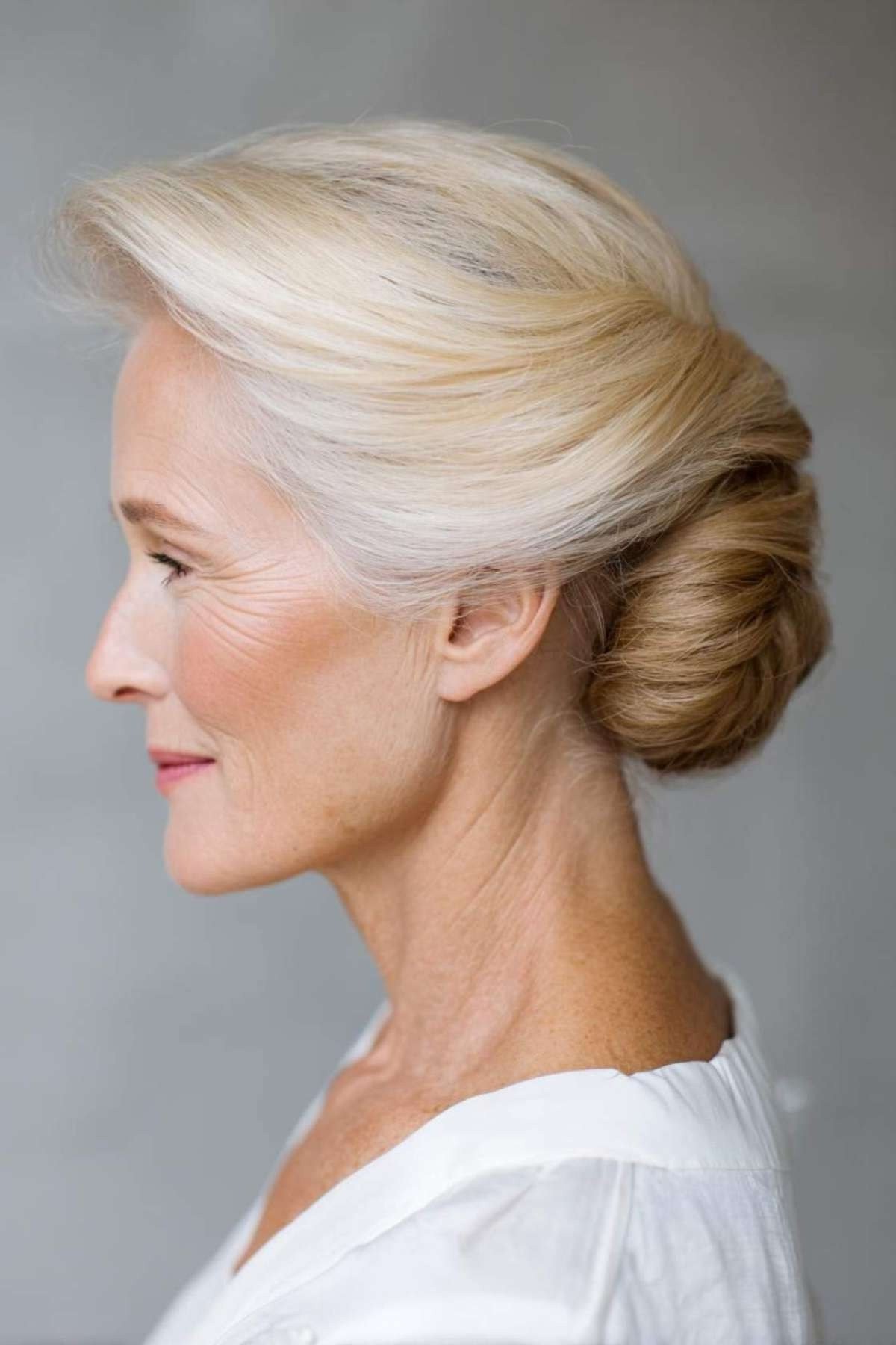Blonde french twist in profile in white top, an elegant updo for women over 70