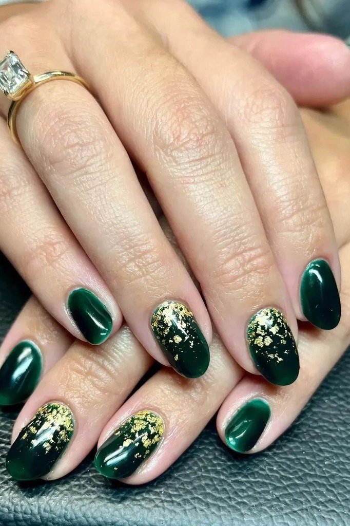 Dark green nails with gold glitter accents styled with gold rings