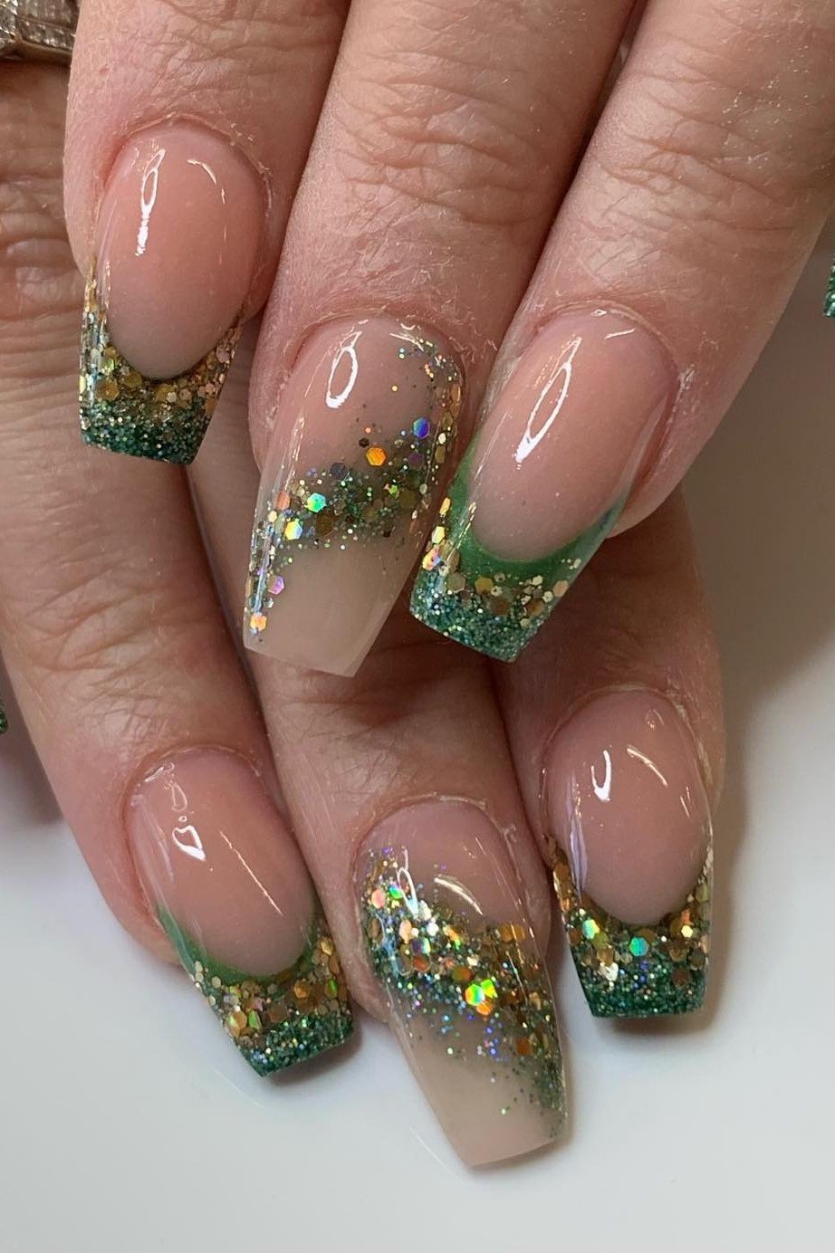 Nude nails with green and gold glitter French tips for women over 60