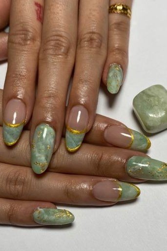 Green marble nails with gold veining on deep skin tone