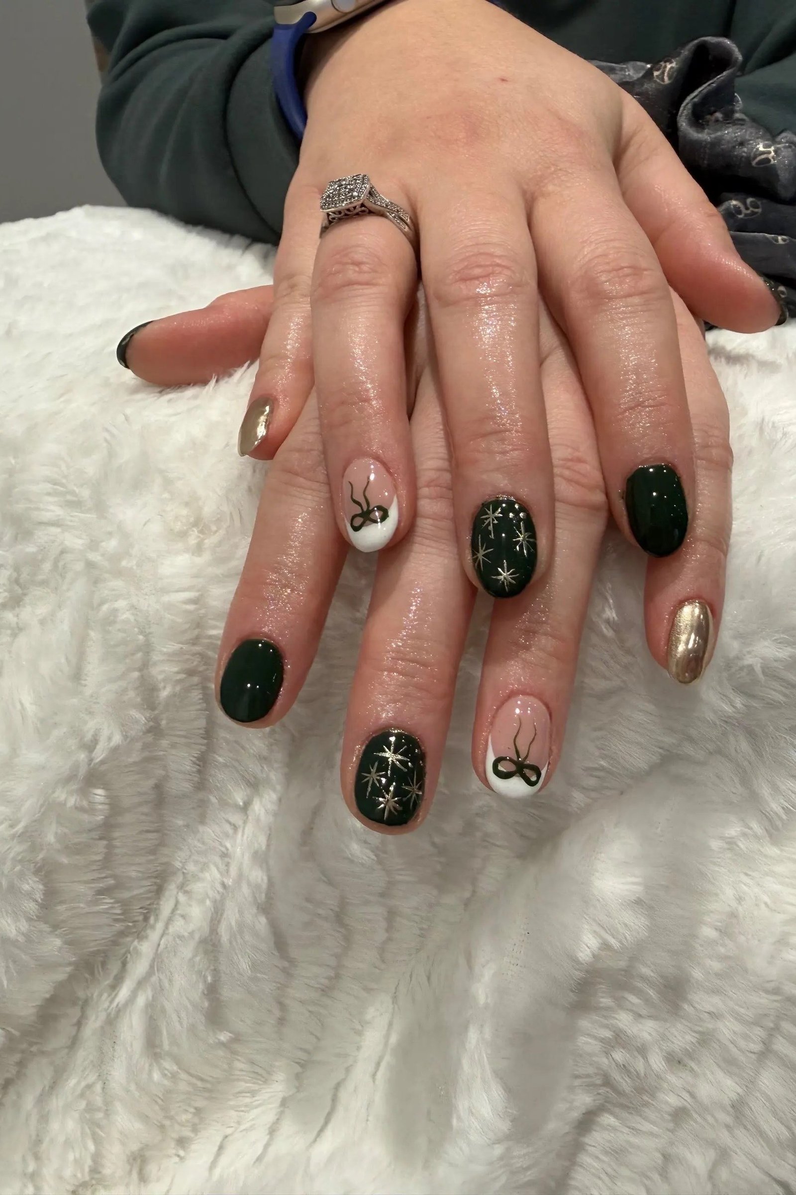Dark green nails with gold accents on mature hands of a woman over 60