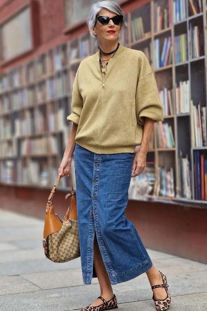 Elegant work outfit for women over 50: mustard knit sweater, long denim skirt, woven tote, front full-body