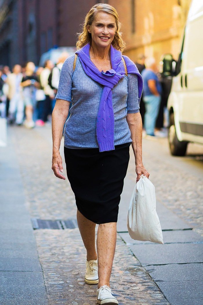 Elegant work outfit for women over 50: denim shirt, blue scarf, black midi skirt, white sneakers, street