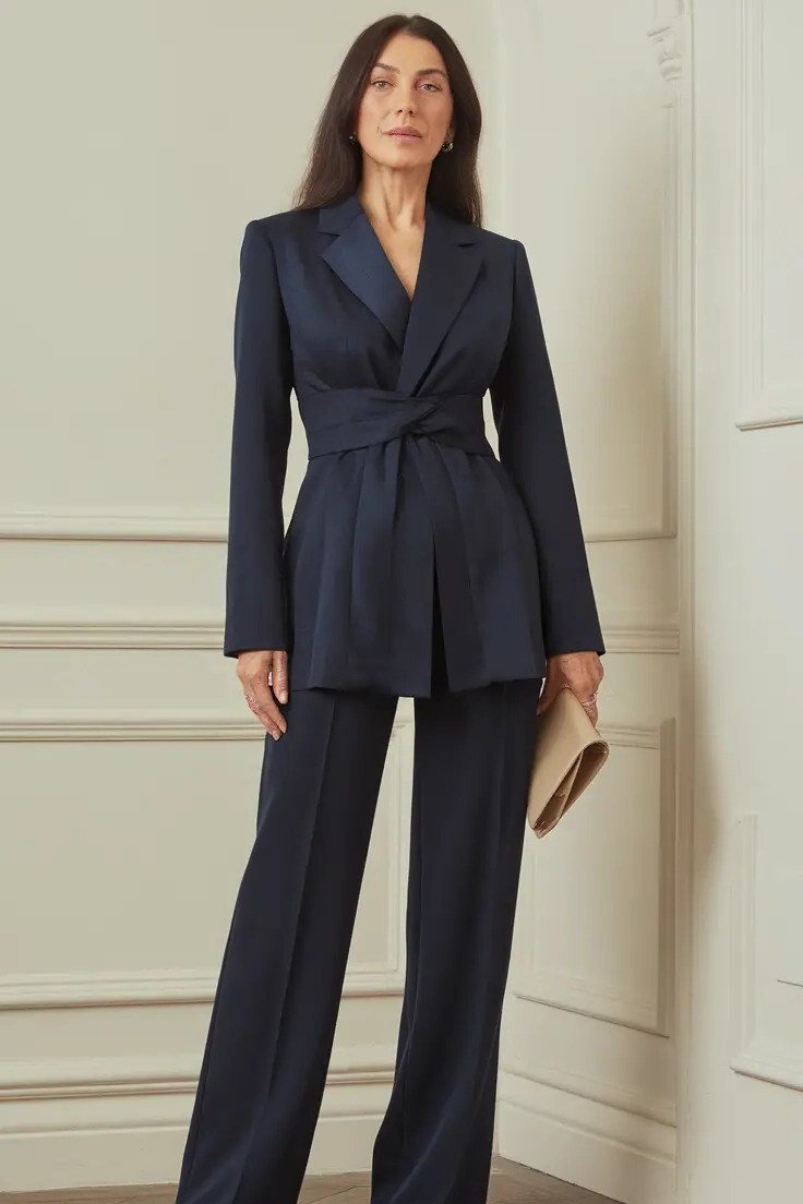 Elegant work outfit for women over 50: navy belted blazer, navy wide-leg trousers, panelled wall