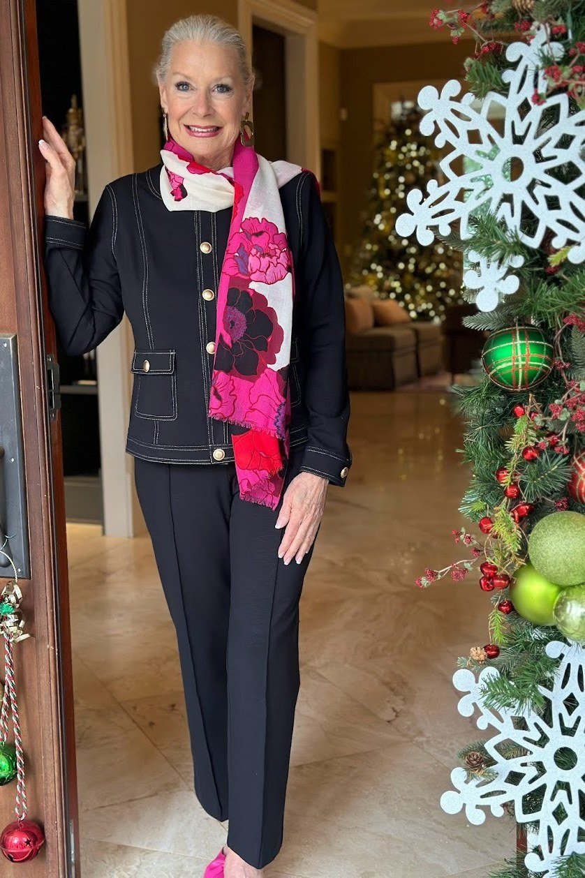 Elegant work outfit for women over 50: black cardigan, pink scarf, black trousers, holiday doorway