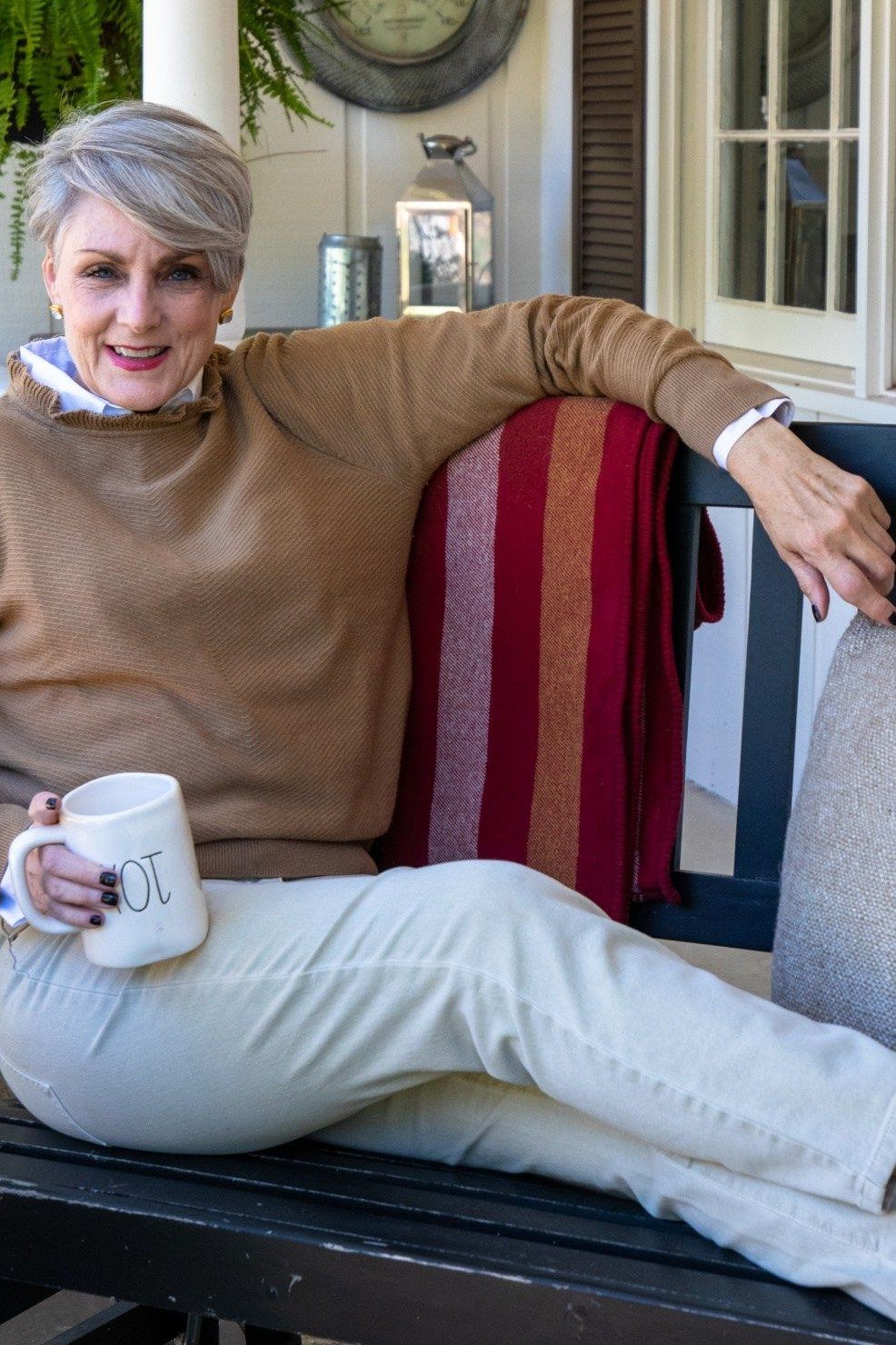 camel sweater with white jeans, older woman relaxing on porch - fall outfit idea for women over 70