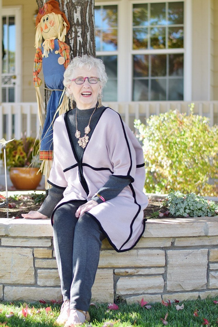 pink sweater with white trousers and tan bag on city sidewalk - fall outfit idea for women over 70