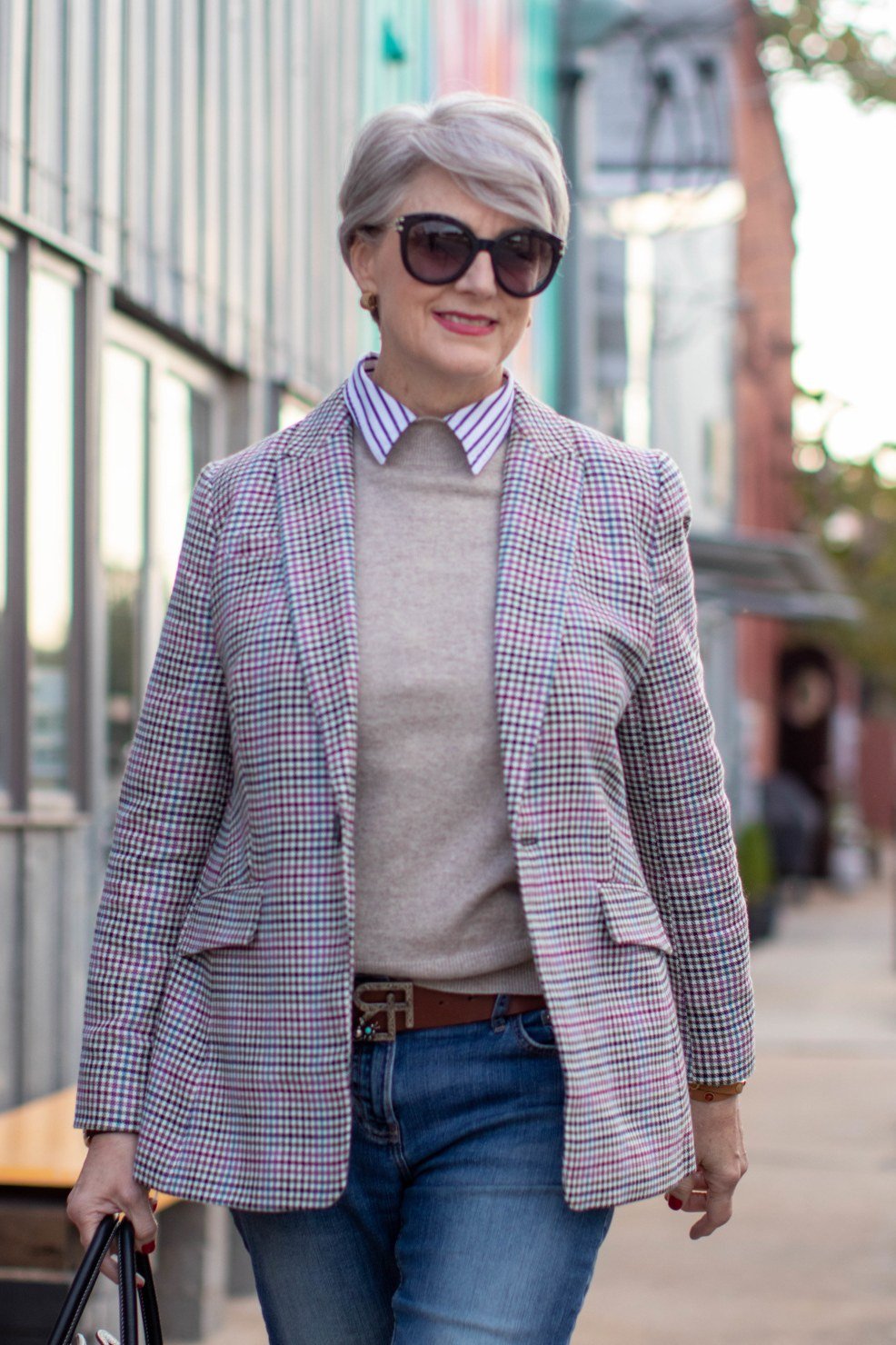 plaid blazer over striped shirt collar and gray top with blue jeans and black bag, older woman on street - fall outfit idea for women over 70