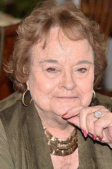 close-up portrait of older woman in olive jacket with gold statement necklace - fall outfit idea for women over 70