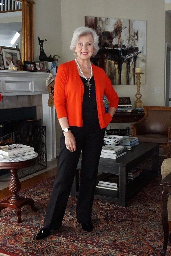 red cardigan with black pants in living room with fireplace - fall outfit idea for women over 70