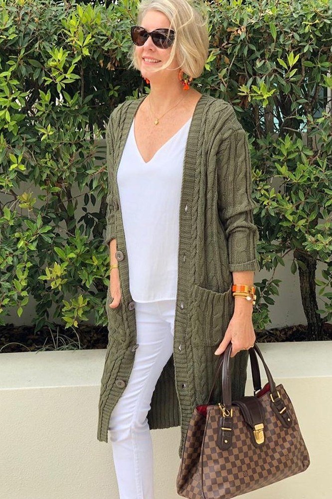 Olive-green long cardigan over white top, white pants, designer bag, full body front view - fall cardigan outfit idea for women over 60