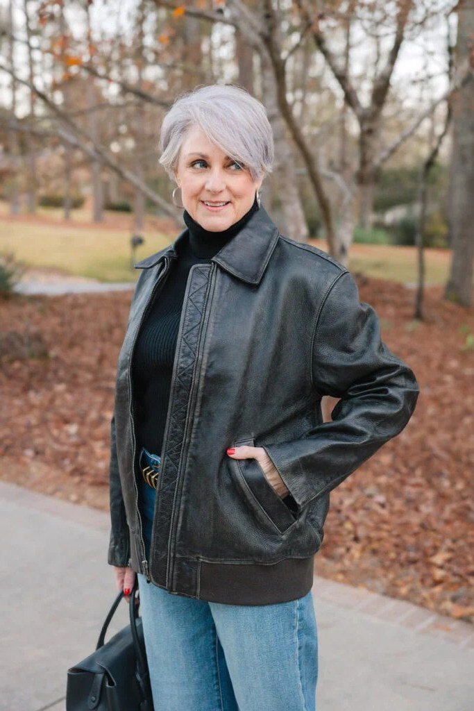 Older woman in a black leather jacket with a sweater and jeans
