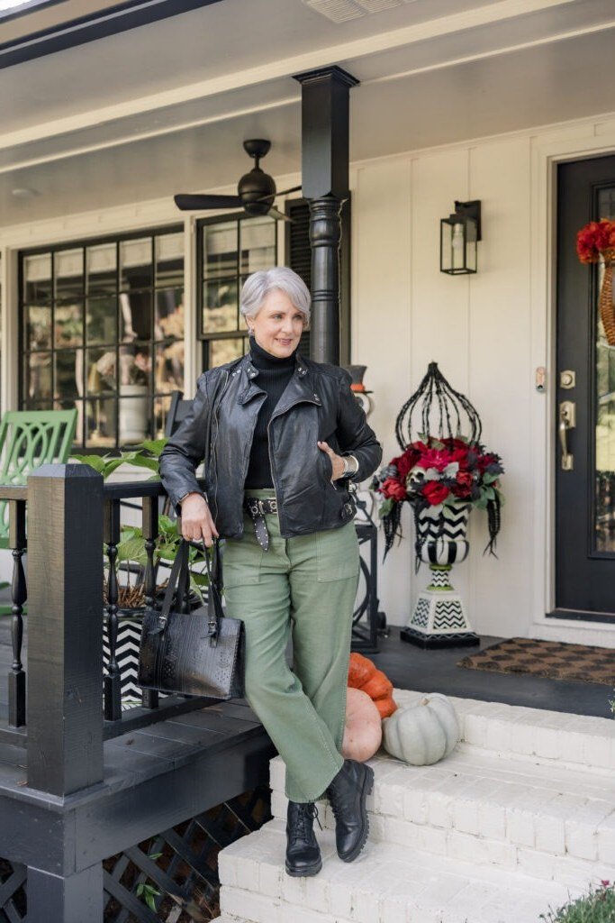 Woman wearing a black leather jacket with deep green trousers