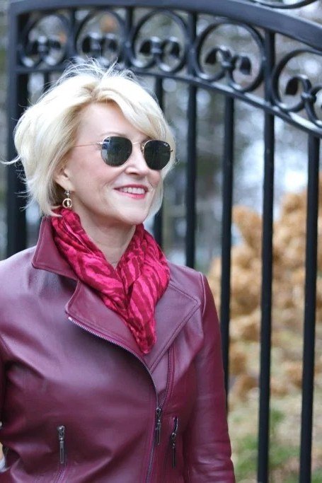 Woman over 60 in a burgundy leather jacket with a red scarf