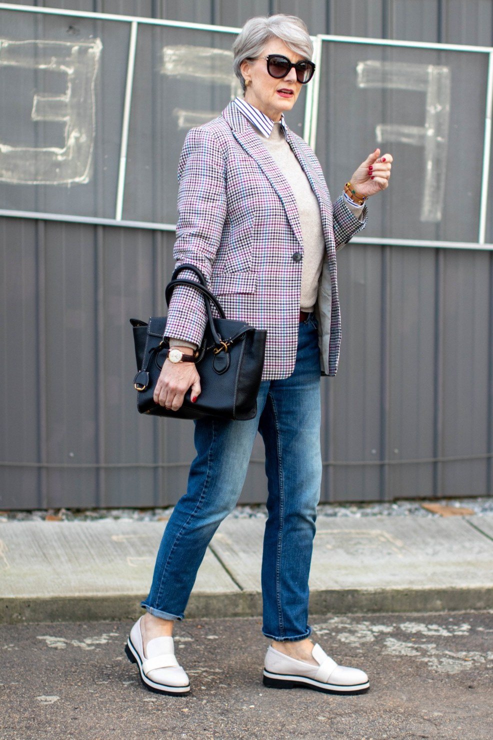 Older woman in a pink plaid blazer with jeans and a white top