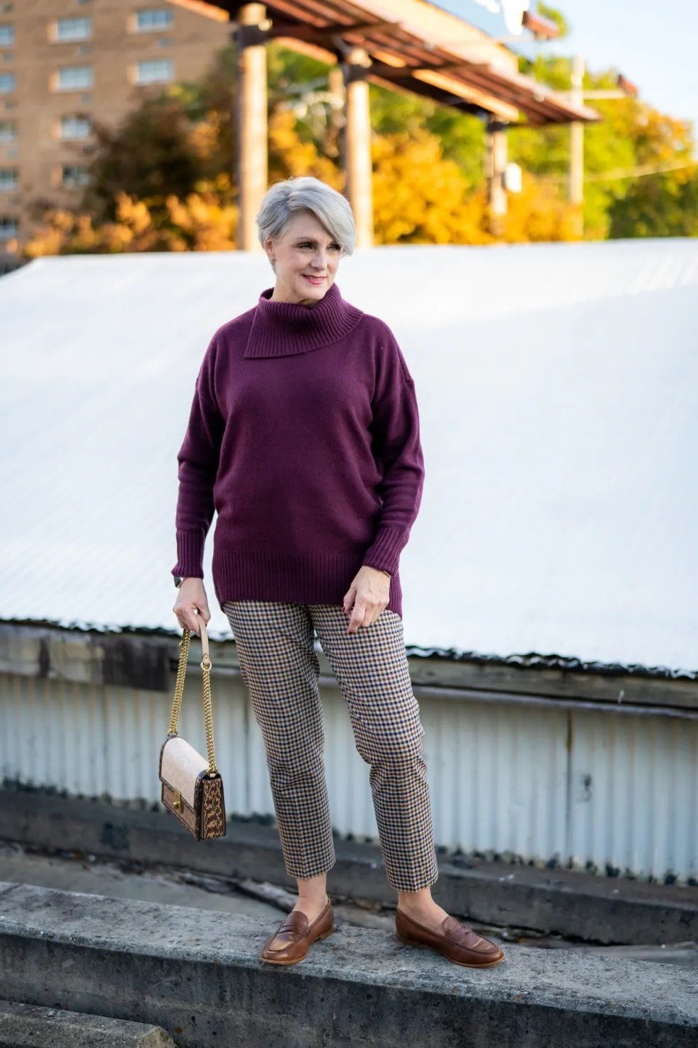 Woman over 60 in a plum turtleneck with checked trousers