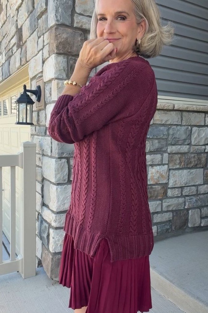 Older woman wearing a burgundy sweater with a pleated burgundy skirt