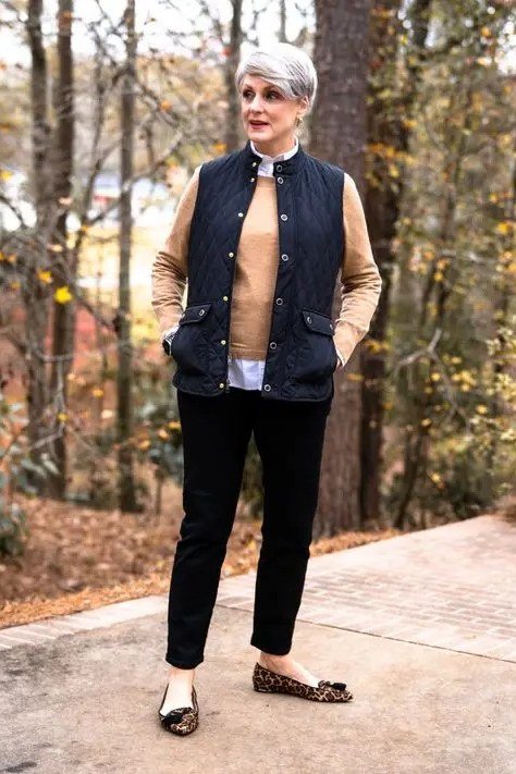 Woman in a navy quilted vest over a camel sweater with black trousers