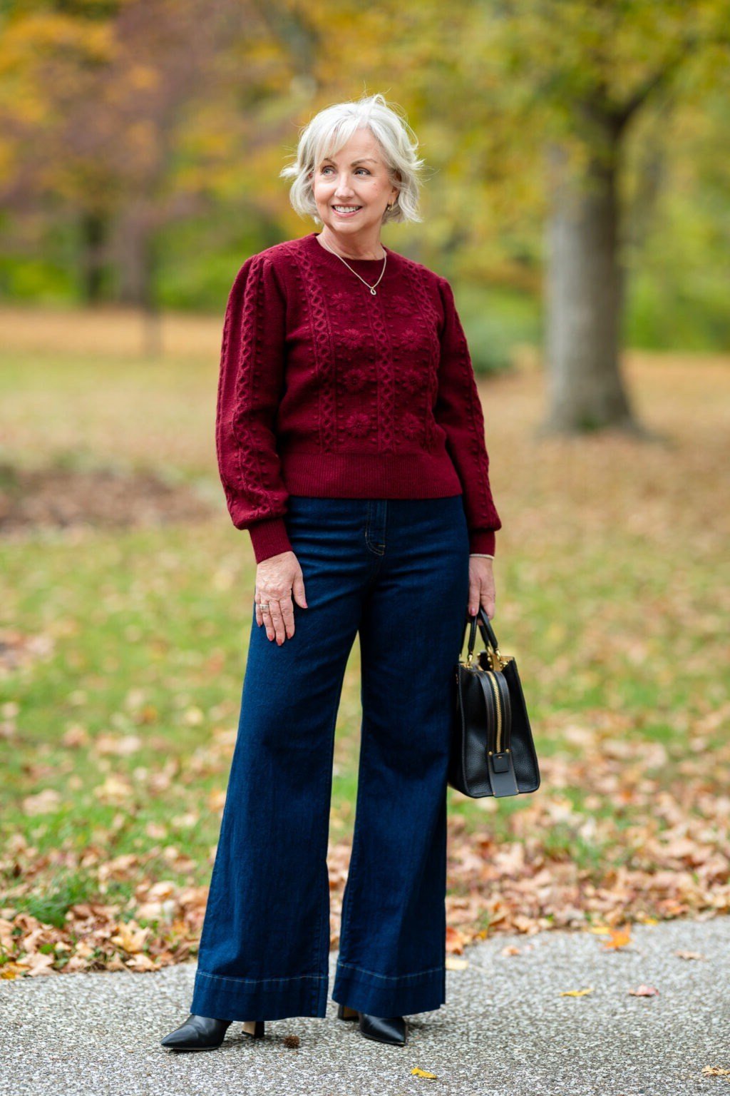 Woman over 60 wearing a red sweater with wide-leg jeans