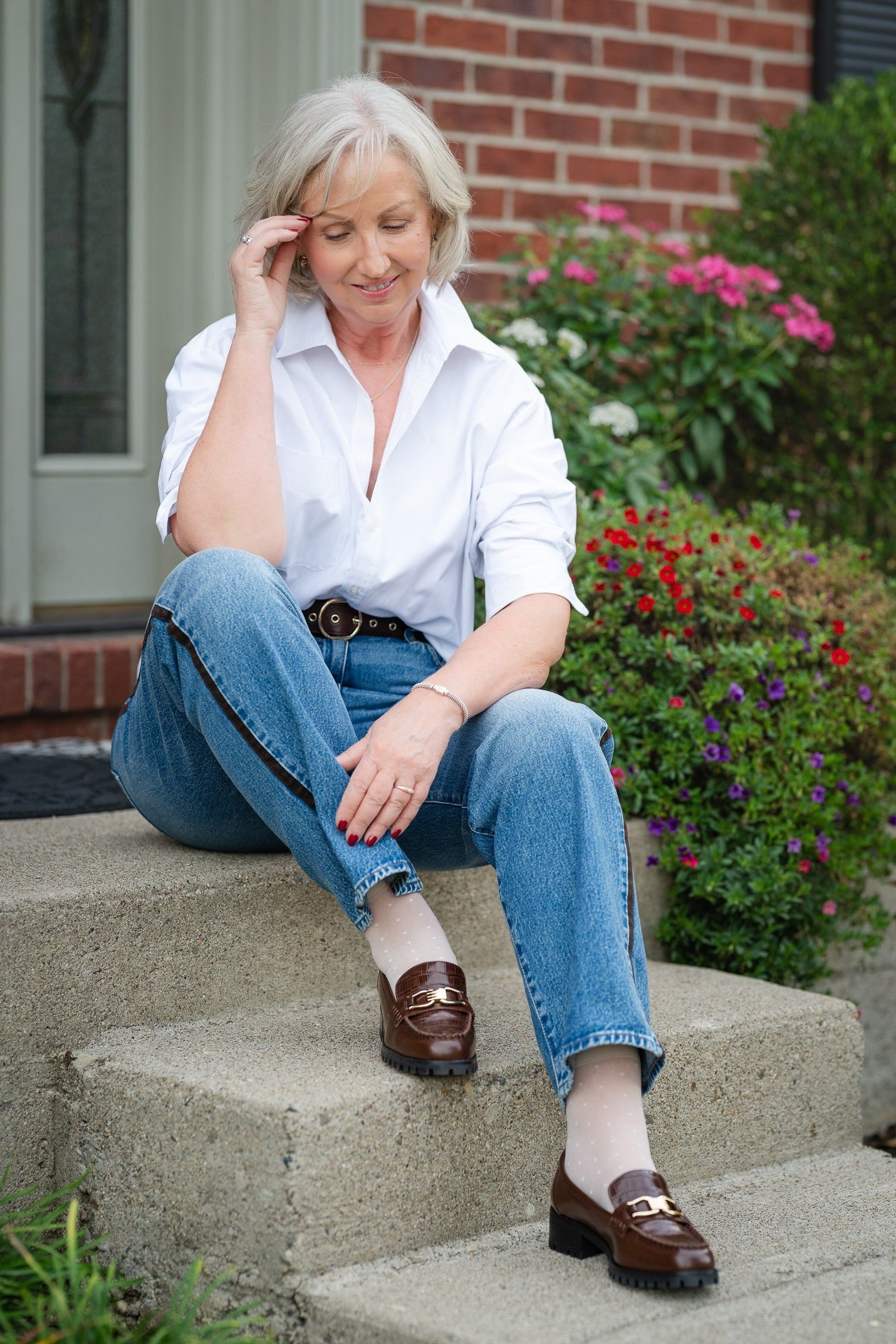Woman over 60 wearing a white shirt with jeans and loafers