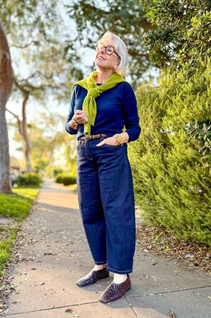 Woman in a blue sweater with wide jeans and a green scarf
