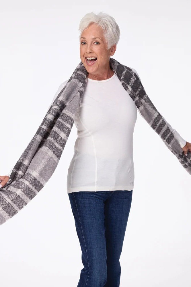 Woman in a white top with a gray plaid scarf and jeans