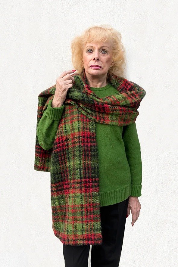 Older woman in a green sweater with a green and red tartan shawl