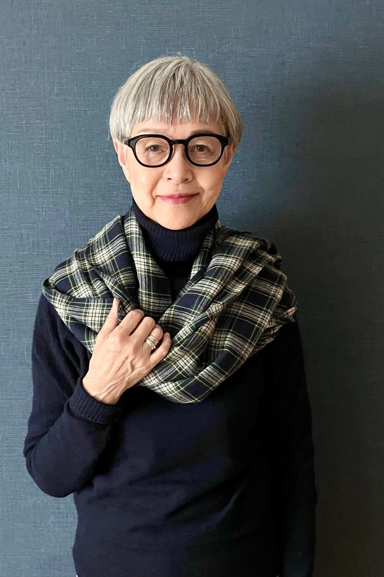 Woman wearing a navy top with a plaid scarf
