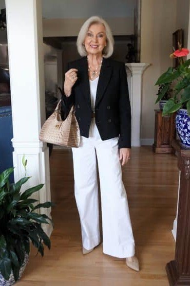 Fall dinner outfit for women over 50: black blazer with white top and white wide-leg trousers, hallway