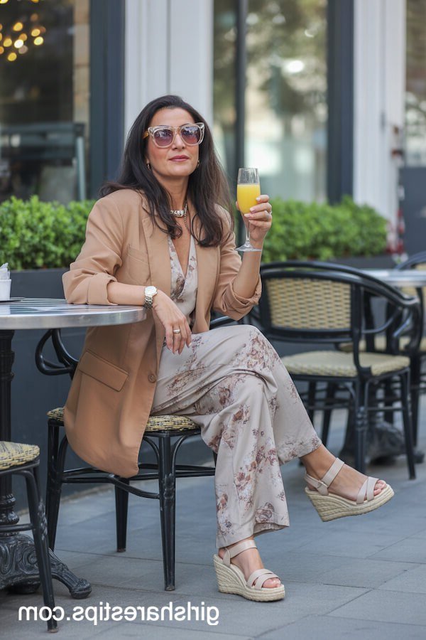 Fall dinner outfit for women over 50: camel blazer with floral wide-leg trousers, cafe
