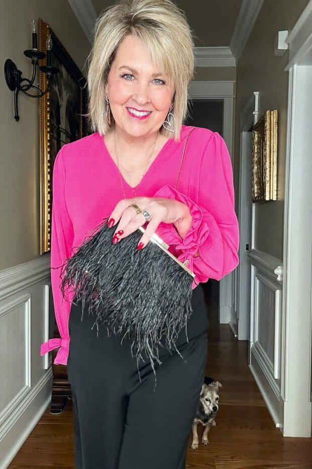 Fall dinner outfit for women over 50: fuchsia wrap blouse with black trousers, hallway