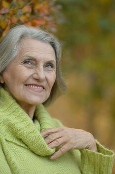 Close-up portrait of an older woman in a lime green cowl-neck sweater - stylish fall look for older women
