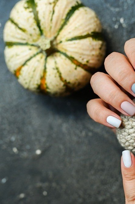 Multicolor fall nails holding a small pumpkin