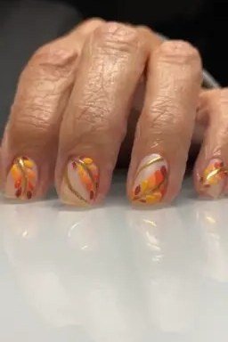 Orange fall marble nails on mature hands