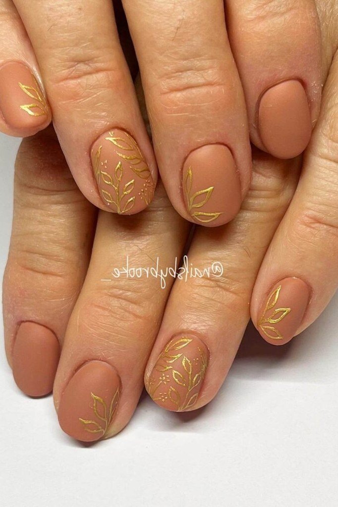 Matte nude nails with gold leaves on mature hands