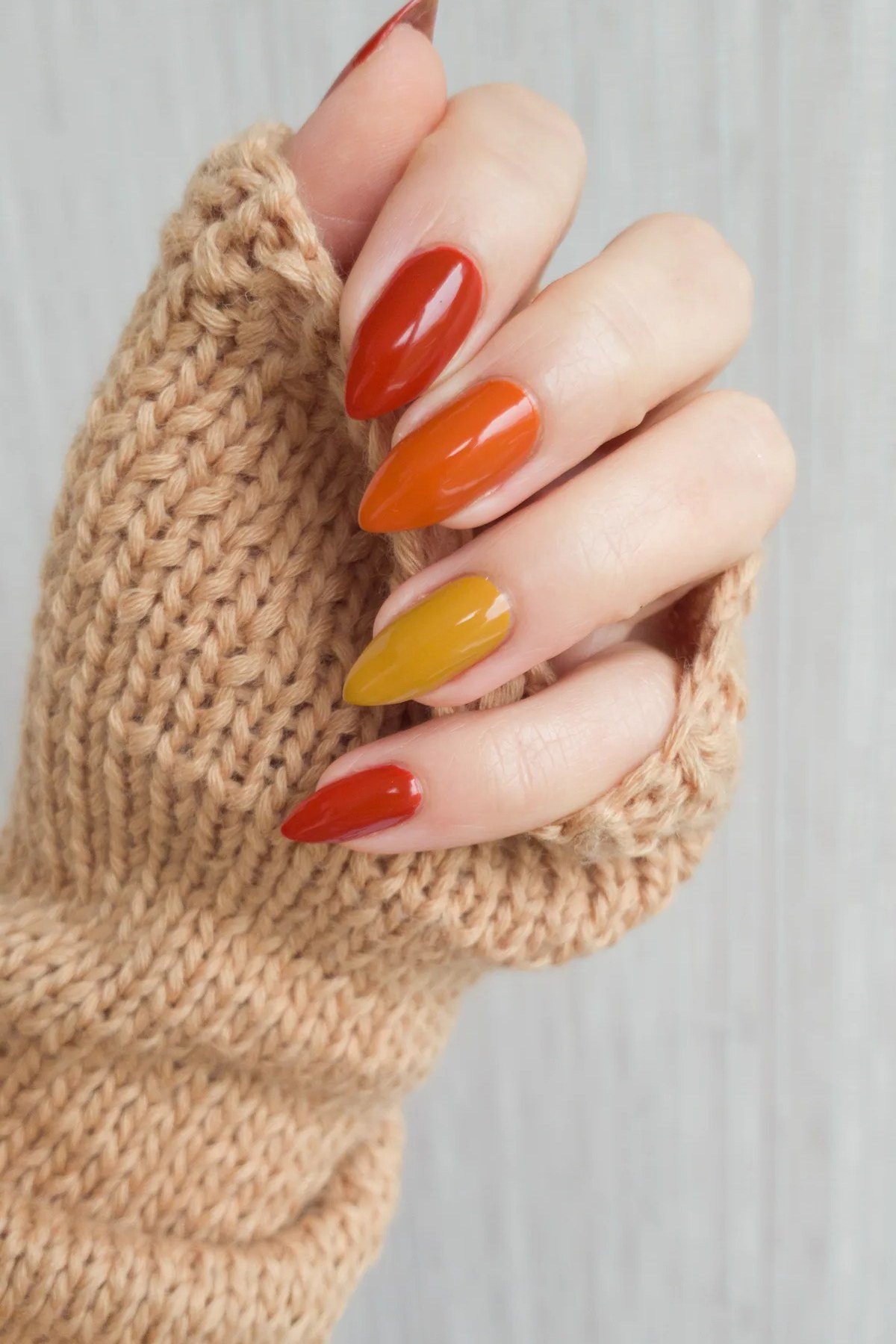 Short orange and yellow nails with a knit sweater