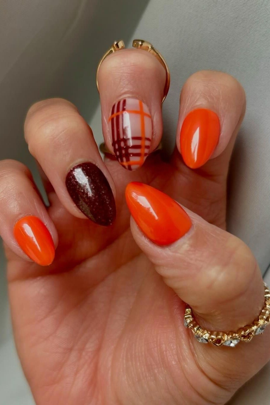 Orange nails with a plaid accent nail