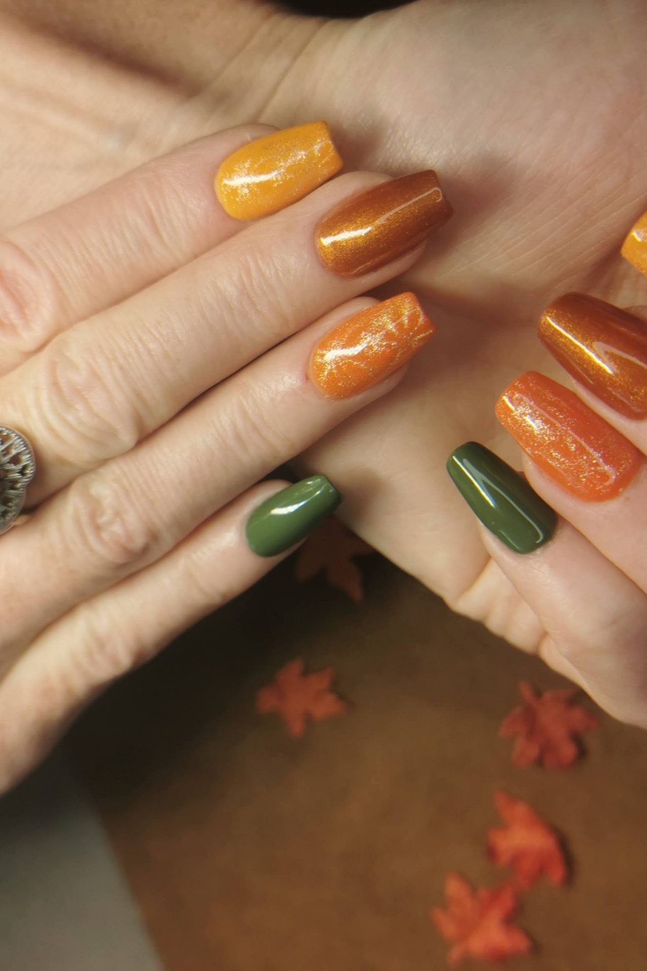 Gold, copper and green nails on mature hands
